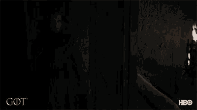 a man with a beard is standing in a dark room with the word got on the bottom right