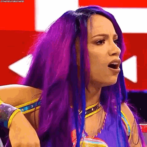 a woman with purple and blue hair is wearing a blue and yellow outfit and making a funny face .