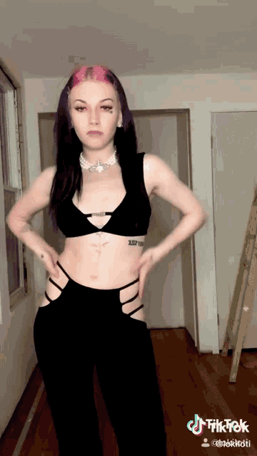 a woman with purple hair and a tattoo on her stomach stands in a hallway with her hands on her hips ..
