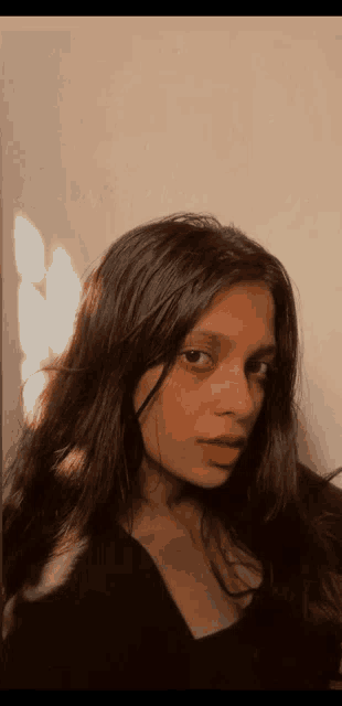 a girl with long dark hair is taking a selfie