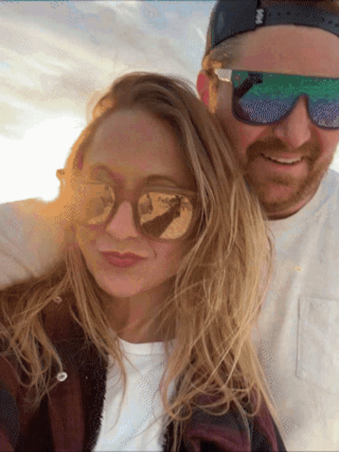 a man and a woman are posing for a picture and the man is wearing sunglasses with a green lens