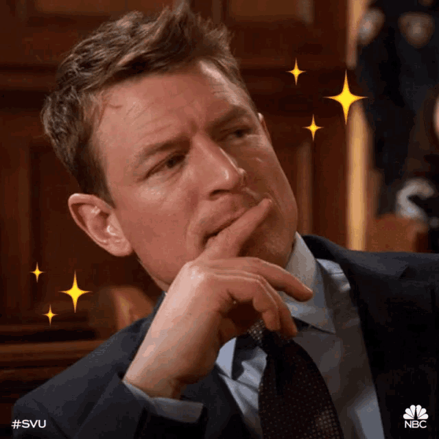 a man in a suit and tie is thinking with a nbc logo in the background