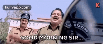 two police officers are standing next to each other in front of a police car and laughing .