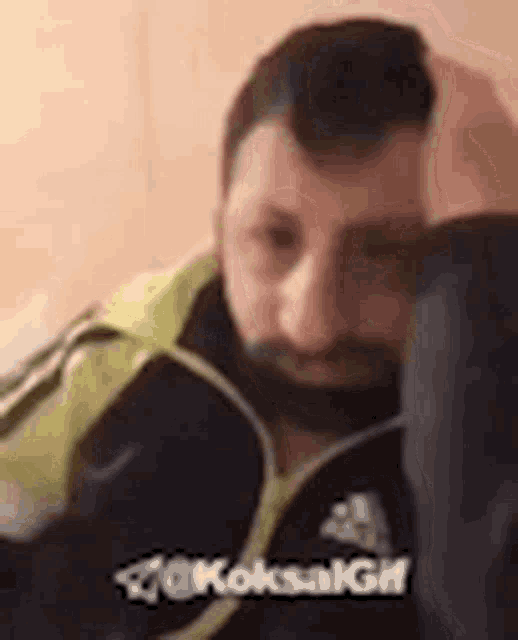 a man with a beard is sitting in a chair with his head on his hand .