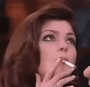 a woman is smoking a cigarette in a dark room .
