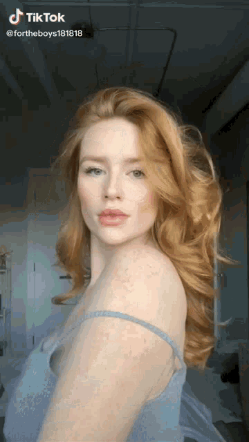 a woman with red hair and freckles is wearing a blue tank top