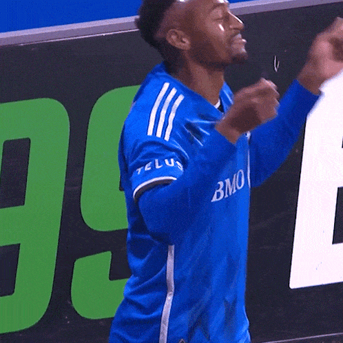 a man in a blue bmo jersey is raising his fist in the air