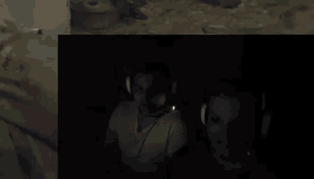two men wearing headphones are sitting in front of a computer screen in a dark room .
