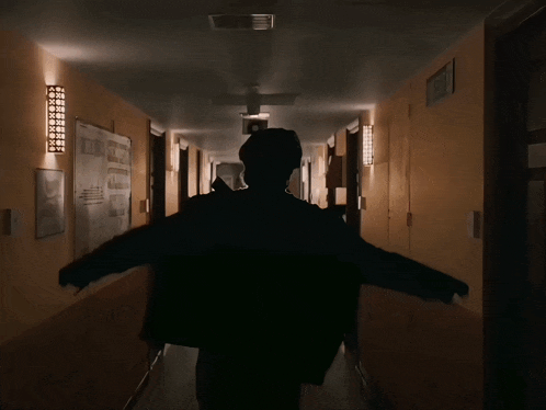 a person walking down a hallway with dq ante brand written on the back of their jacket