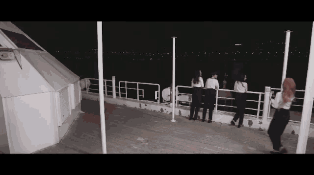 a group of women are standing on a deck looking out over a body of water