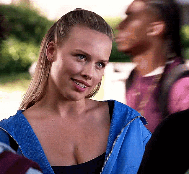 a woman wearing a blue jacket and a black top smiles