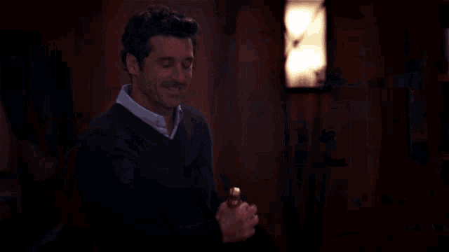 a man in a black sweater is holding a bottle of champagne and smiling