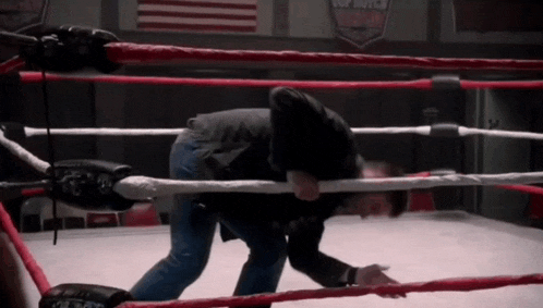 a man in a boxing ring with a sign behind him that says top ropes wrestling