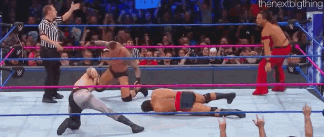 a group of men are wrestling in a ring with a referee watching .