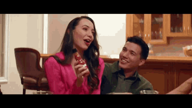 a man and a woman are sitting at a table holding bottles of coca cola .