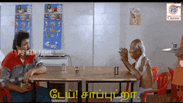 a man sitting at a table with a sign that says ps nam tamil on it