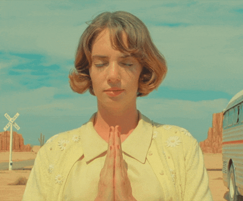 a woman praying in front of a train crossing sign