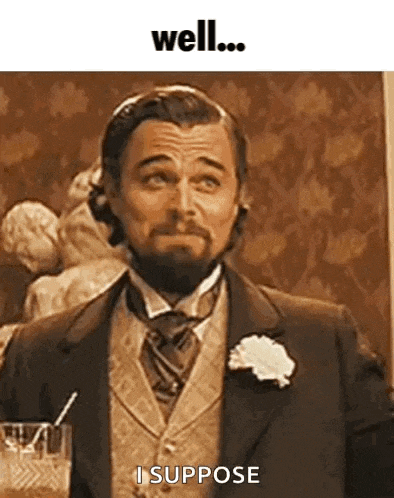 a man with a beard is wearing a suit and tie and holding a drink .
