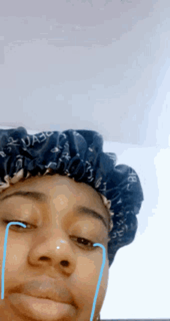 a woman wearing a shower cap is crying with tears running down her face .