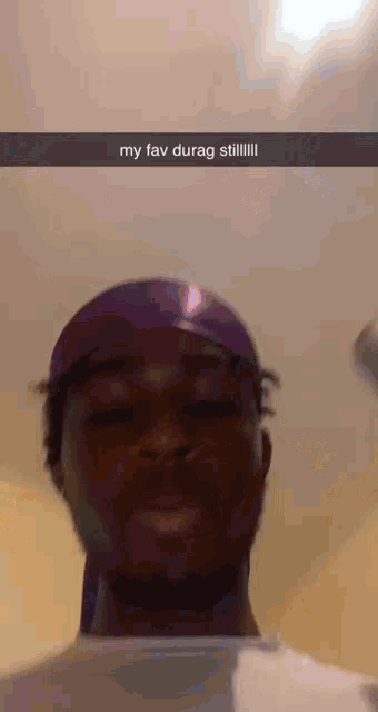 a man wearing a purple headband and a white shirt is making a funny face