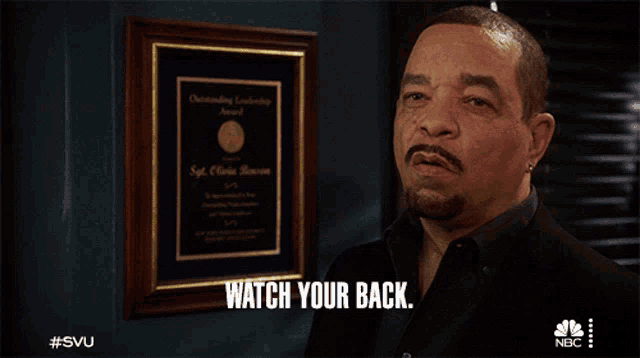 ice cube says " watch your back " in front of a framed certificate