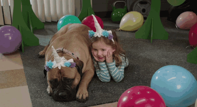 a little girl laying next to a dog with a unicorn headband