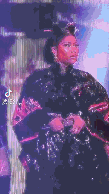 a woman in a black and pink dress is standing in front of a microphone .