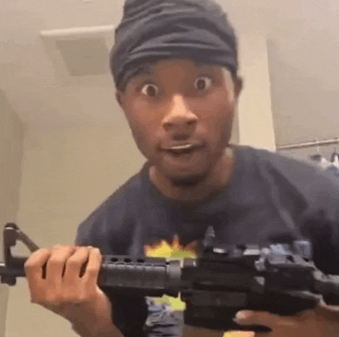 a man wearing a headband is holding a gun in his hands .
