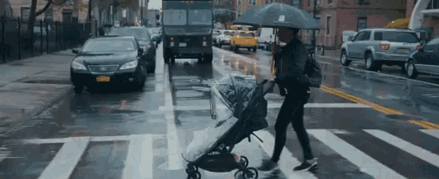 a woman pushing a stroller in the rain with an umbrella that says new balance