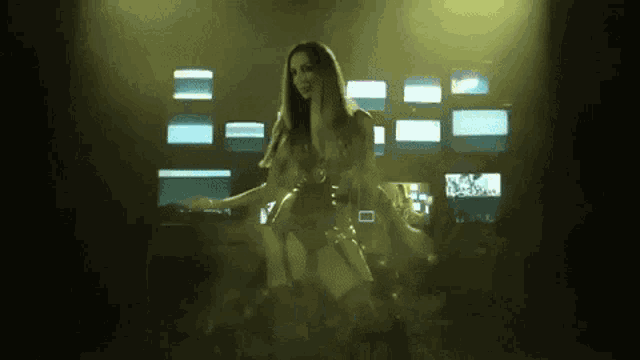 a woman is dancing on a stage in front of a bunch of monitors .