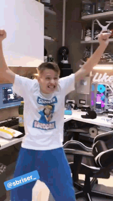 a man wearing a shirt that says sbriser is standing in front of a desk