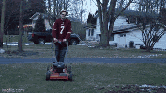 a man wearing a red jersey with the number 7 is mowing the grass