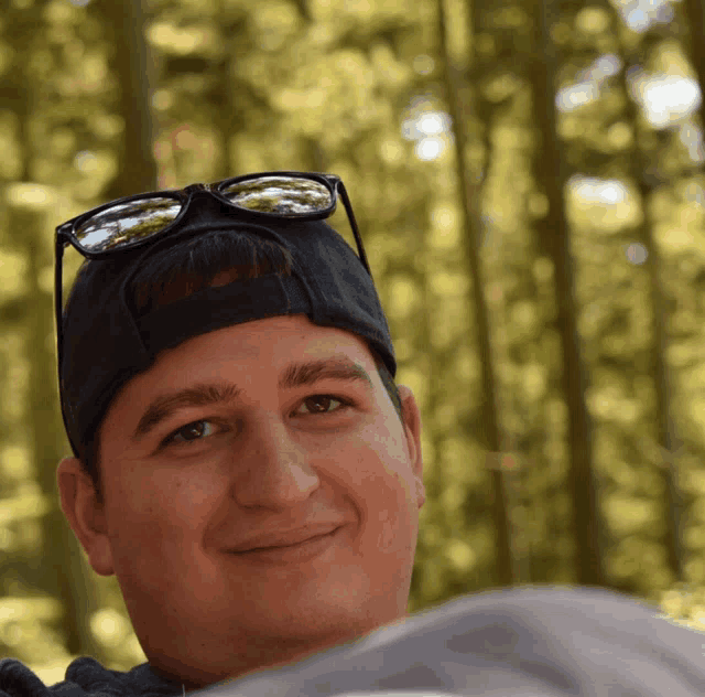 a young man wearing sunglasses and a hat is smiling