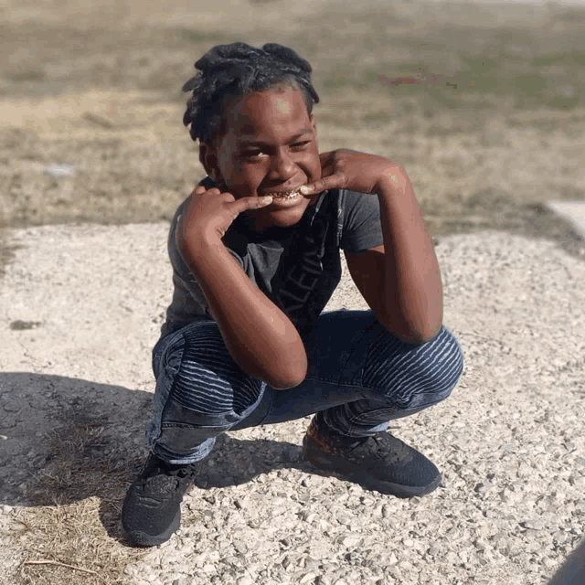 a young boy wearing a calvin klein shirt is squatting down on the ground