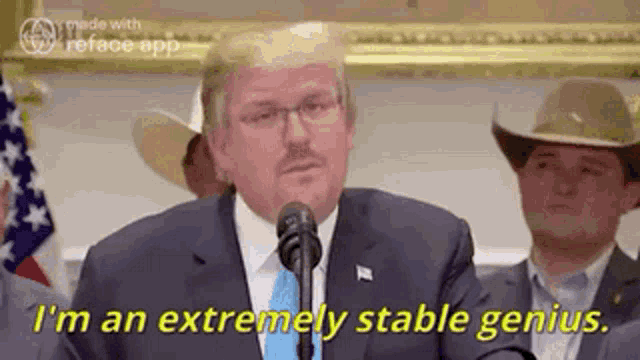 a man in a suit and tie is talking into a microphone and says i 'm an extremely stable genius