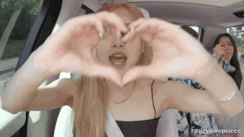 a woman making a heart with her hands in a car