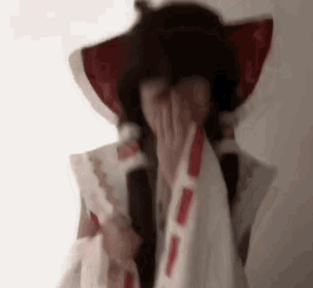 a woman in a costume is covering her face with her hands .
