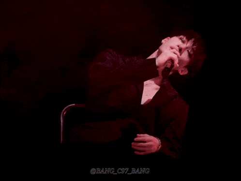 a man in a suit is sitting in a chair with the name bang_c97_bang written on the bottom