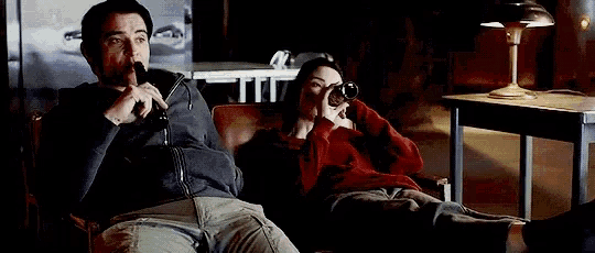 a man and a woman are sitting on a couch talking on the phone