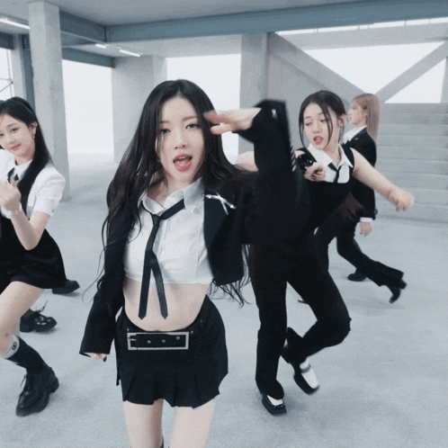 a girl in a white shirt and black tie is dancing with other girls