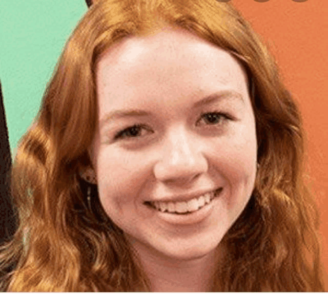 a close up of a woman 's face with red hair and a smile .
