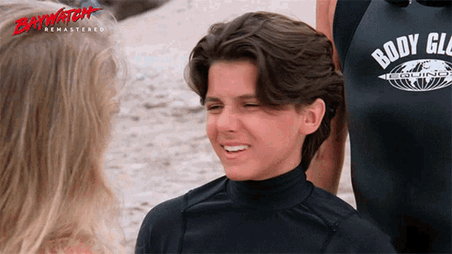 a boy wearing a black body guard shirt smiles at a girl