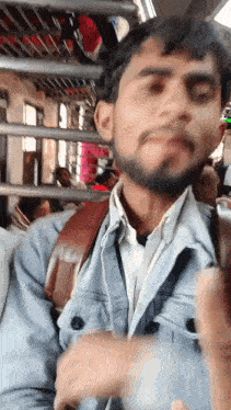 a man with a beard is sitting on a bus looking at his phone
