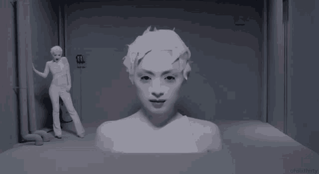 a woman is standing in a room with a statue of her behind her that says ohauxthirty