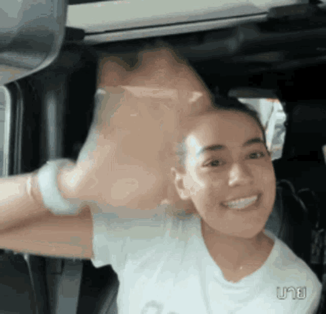a woman in a white shirt is sitting in a car with her arm outstretched