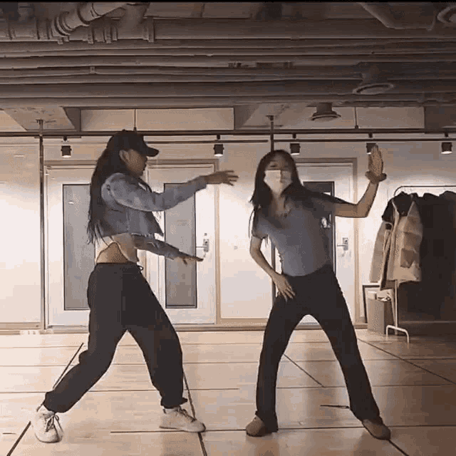 two women wearing face masks are dancing together in a dance studio
