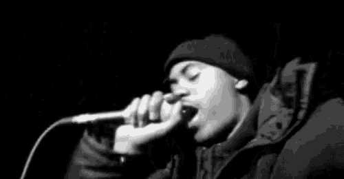 a black and white photo of a person singing into a microphone .