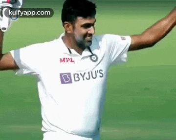 a man in a white shirt with the word byju 's on it is standing on a field .