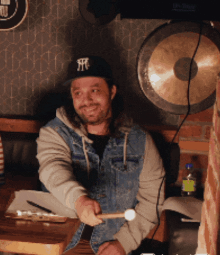 a man wearing a new york yankees hat holds a drum stick