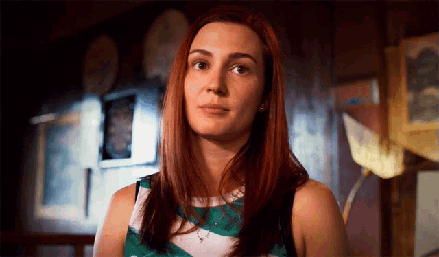 a woman with red hair is wearing a green and white plaid shirt